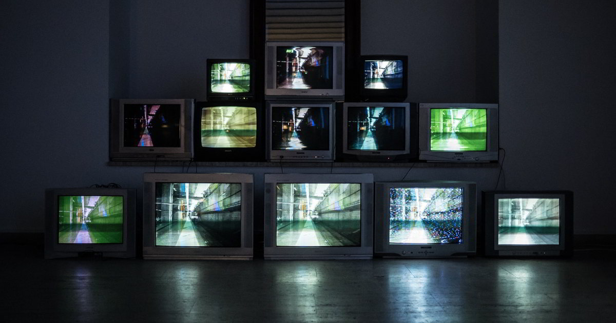 Fernsehgeräte Scheier Kunstinstallation: 12 große und kleine Fernsehgeräte stehen aufeinandergestapelt. Alle haben das gleiche Bild von einem langen Gang.