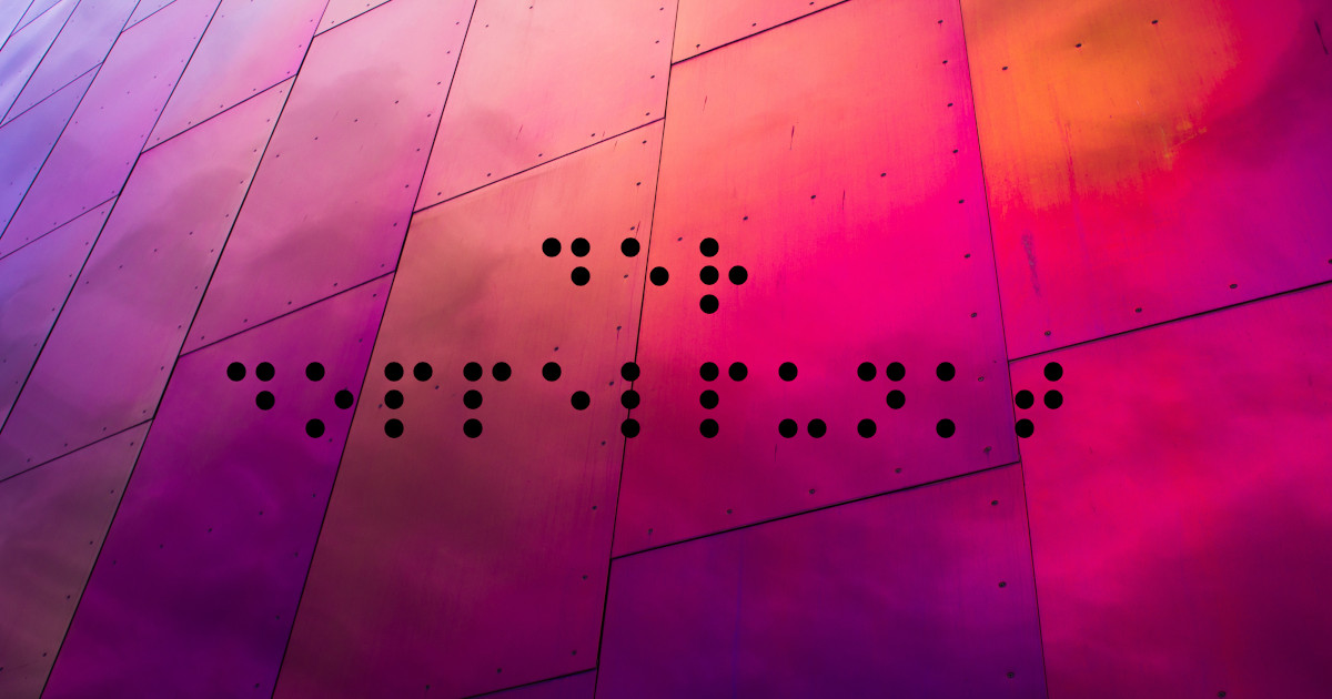 Doppelpunkt in Brailleschrift Auf einem roten und lilafarbenen Hintergrund steht mit schwarzen Punkt in Brailleschrift das Wort "Doppelpunkt"