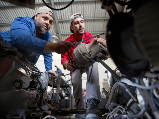 Zwei Mechaniker arbeiten gemeinsam an einem Motor.